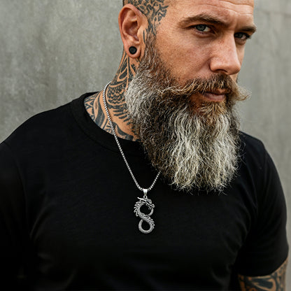 Man with tattoos and a beard wearing a black shirt and a silver necklace with a dragon pendant.