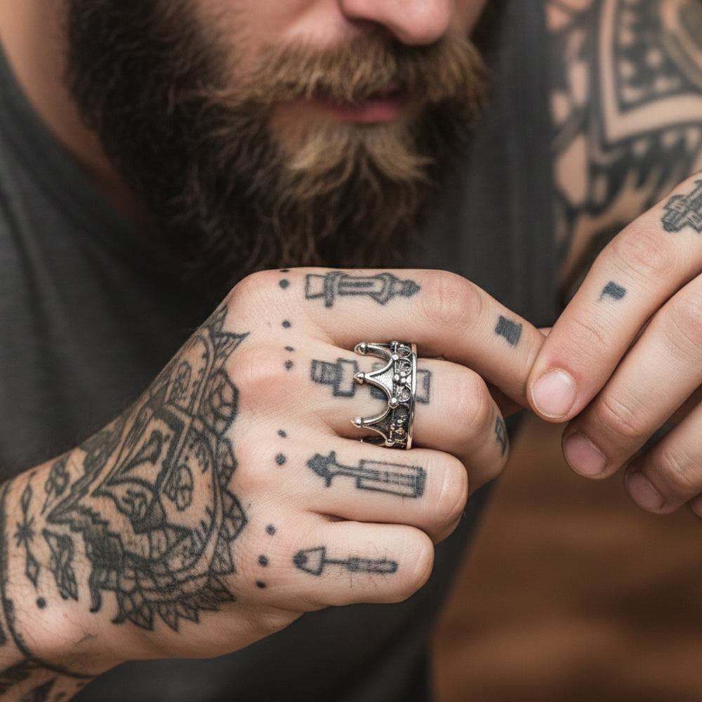 Man with tattoos on hands wearing a silver ring with a crown design.