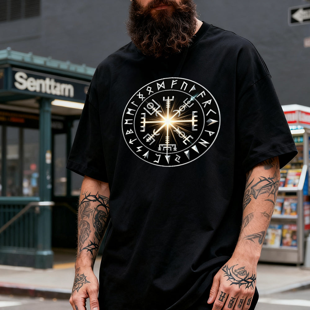Person wearing a black t-shirt with a circular design featuring symbols, standing on a street.