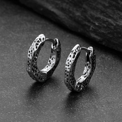Pair of silver hoop earrings on a dark textured surface