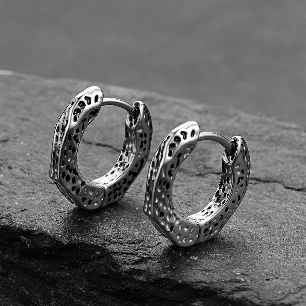 Silver hoop earrings on a dark stone surface