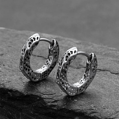 Silver hoop earrings on a dark stone surface