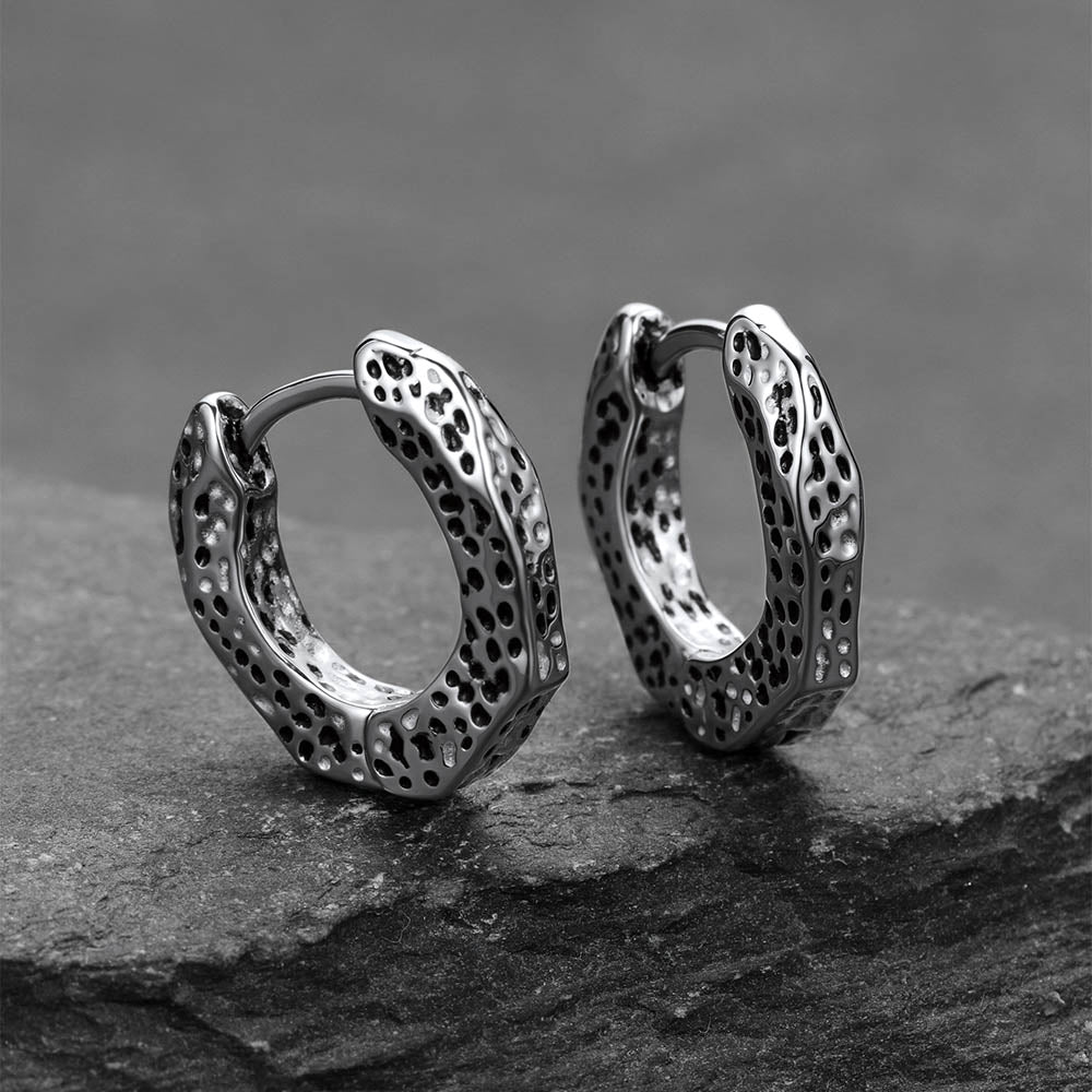 Pair of silver hoop earrings on a dark stone surface