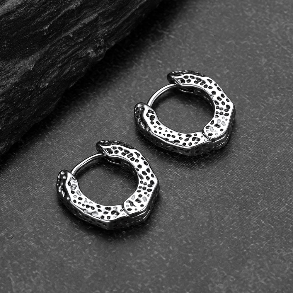 Pair of silver hoop earrings on a textured surface