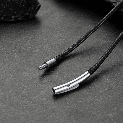 Close-up of a black braided cord with metal clasp on a dark surface