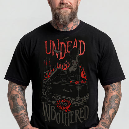A man wearing a black graphic t-shirt with a gothic design featuring the text 'UNDEAD UNBOThERED' and a woman sitting in a coffin surrounded by flames.