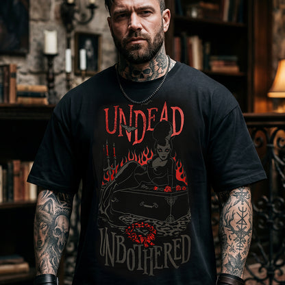 A man with tattoos wearing a black graphic t-shirt with the words 'UNDEAD UNBOOTHERED' and a dark illustration in red and gray, set against a dark, atmospheric background.