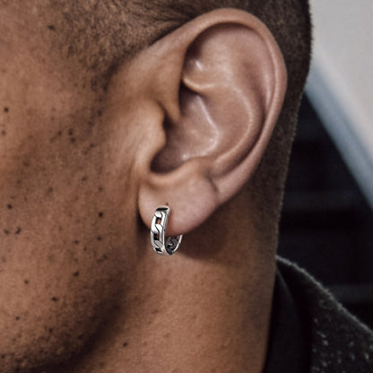 Close-up of an ear wearing a silver hoop earring with a blurred background