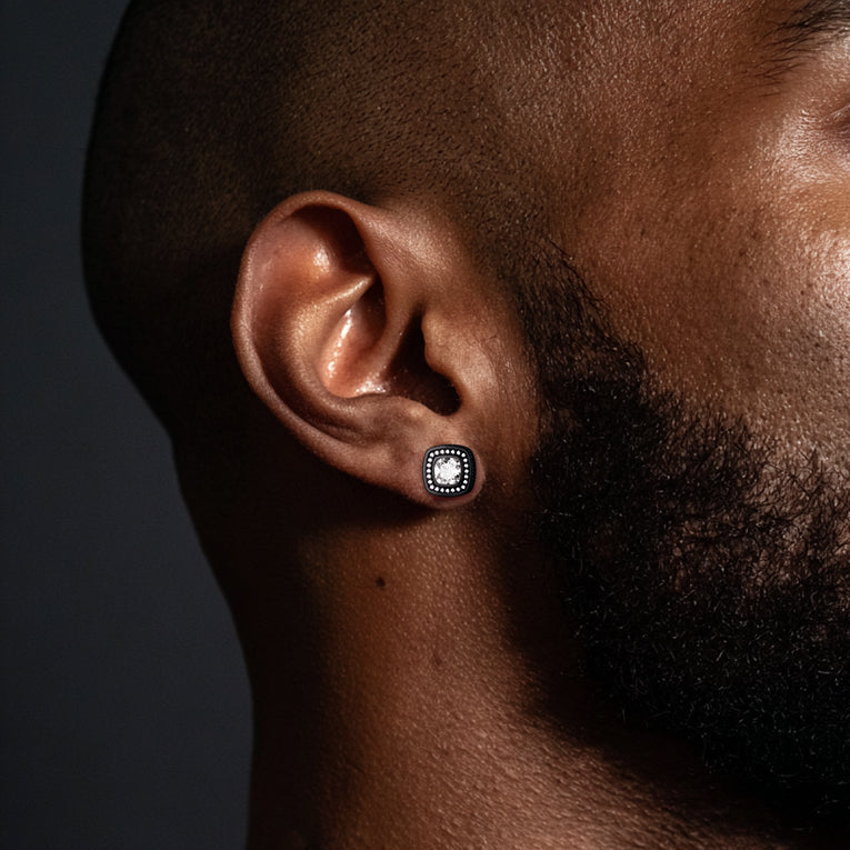 Close-up of a man wearing a silver earring with a clear gemstone on a dark background