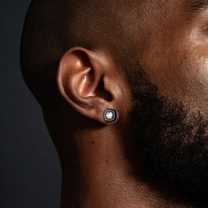 Close-up of a man wearing a silver earring with a clear gemstone on a dark background