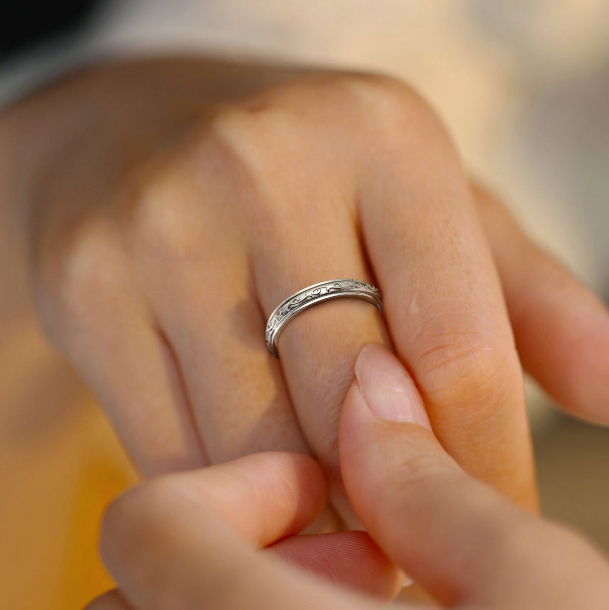 Close-up of a hand wearing a silver ring with a blurred background