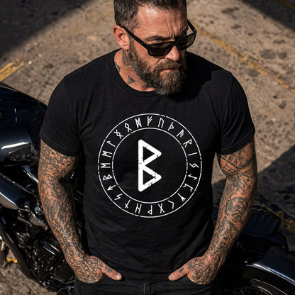 Man wearing a black t-shirt with a white rune symbol and text, standing next to a motorcycle.