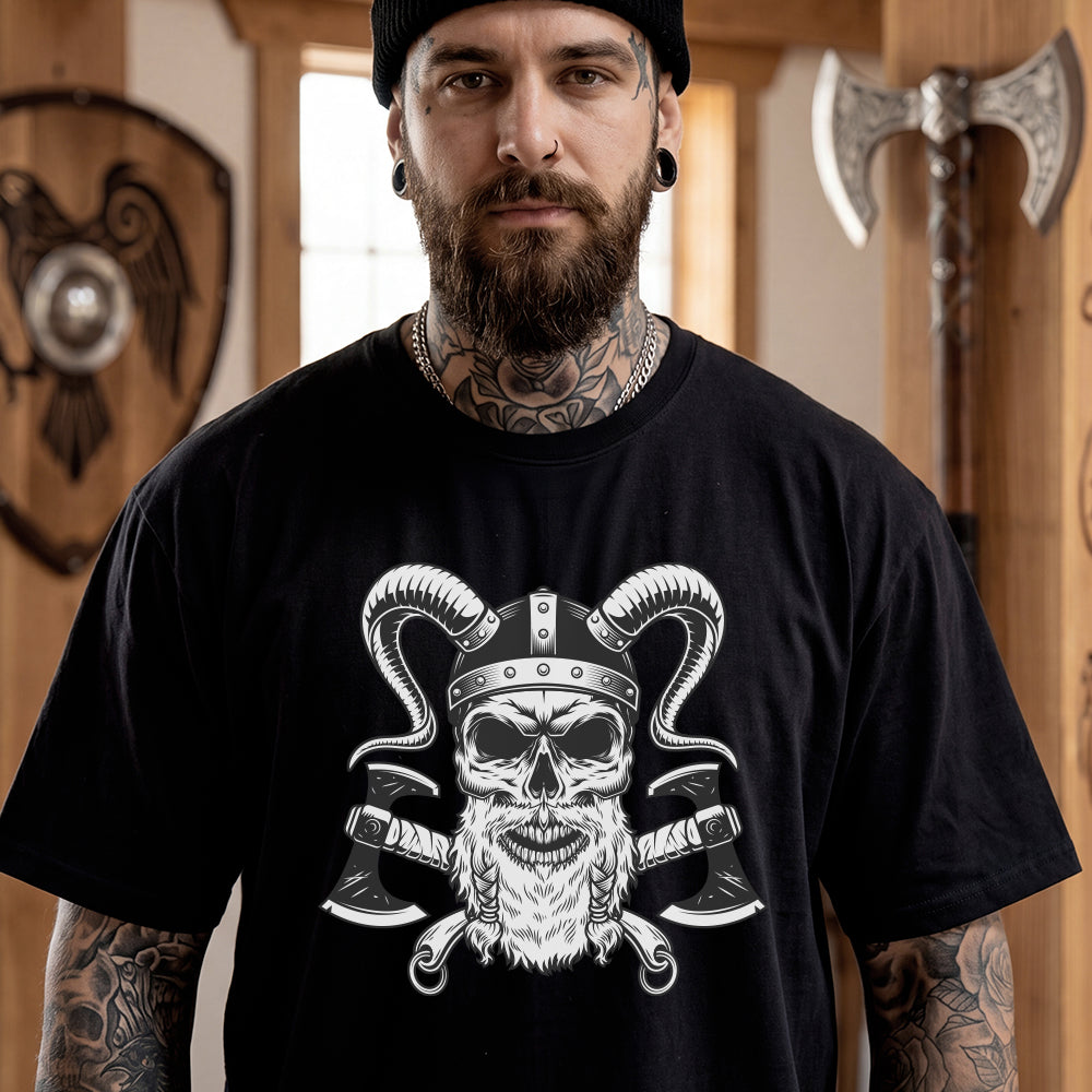 Man wearing a black t-shirt with a graphic design of a skull and axes, standing in a room with Viking-themed decor.
