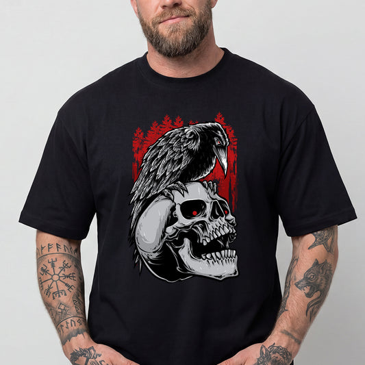 A man wearing a black short-sleeve t-shirt with a graphic print of a raven perched on a skull, set against a red forest background. img