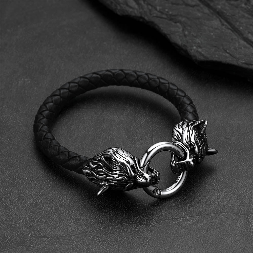 Viking wolf-head leather bracelet set against a dark gray rock background.