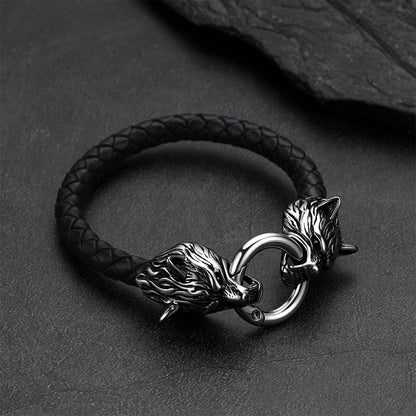 Viking wolf-head leather bracelet set against a dark gray rock background.