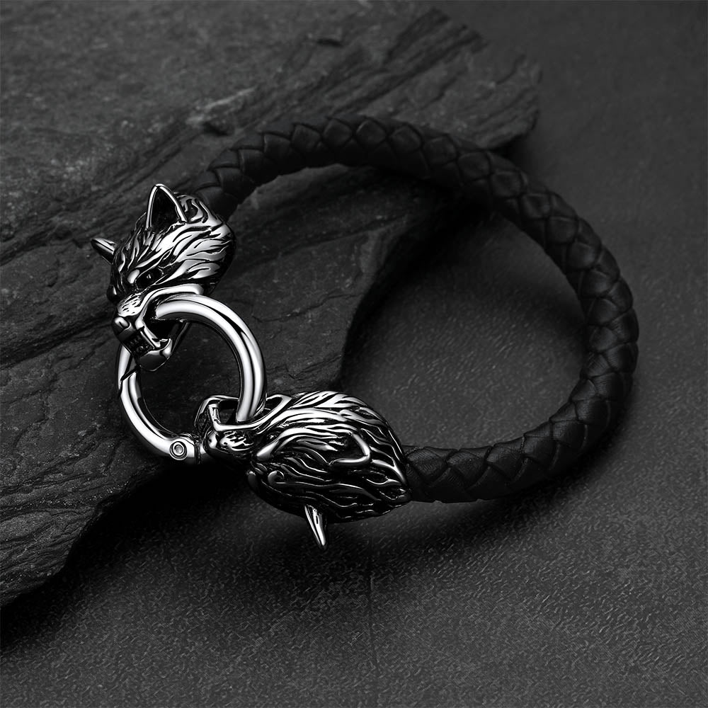 Viking wolf-head leather bracelet set against a dark gray rock background.
