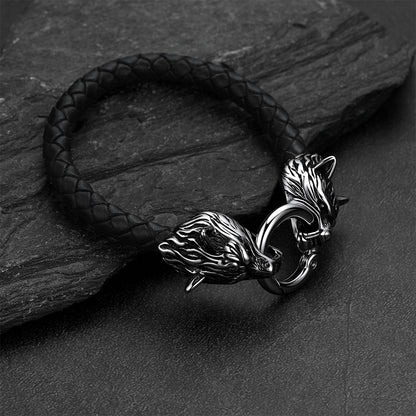 Viking wolf-head leather bracelet set against a dark gray rock background.