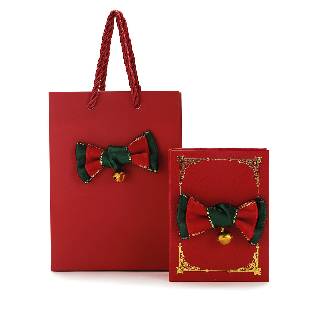 Red gift bag and box with decorative bow and gold bell on a white background