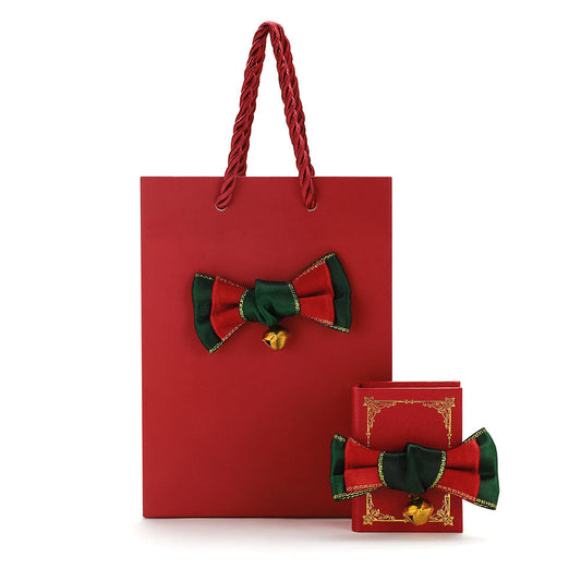 Red gift bag with green and red bow design on a white backgroundimg