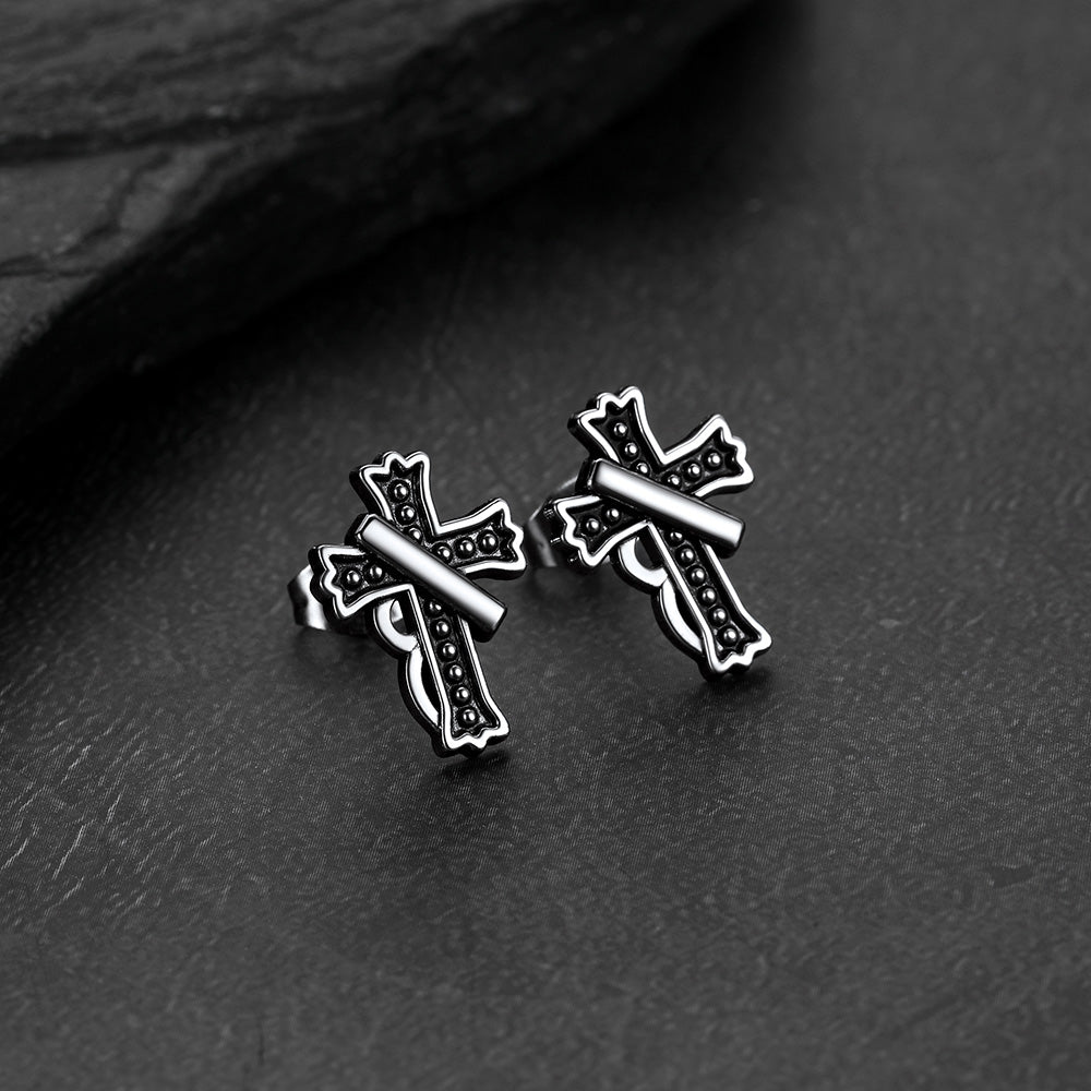 Close-up of vintage crucifix cross stud earring with antique finish, detailed retro religious jewelry for men