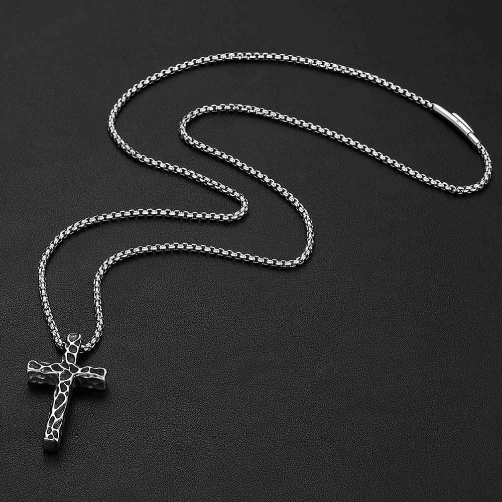 Men's vintage hammered-texture cross necklace on a grey rock
