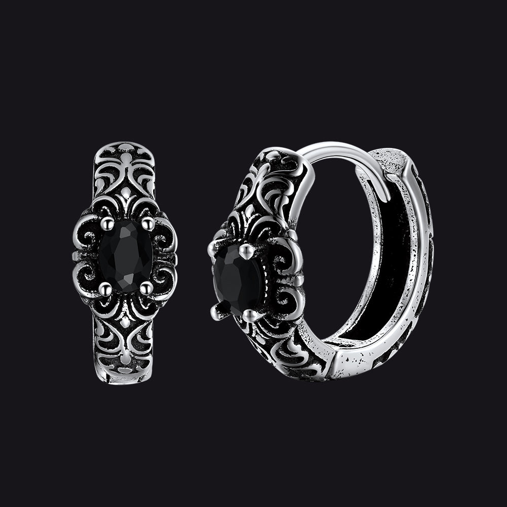 Pair of silver hoop earrings with black gemstones on a black background