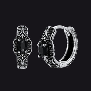 Pair of silver hoop earrings with black gemstones on a black background