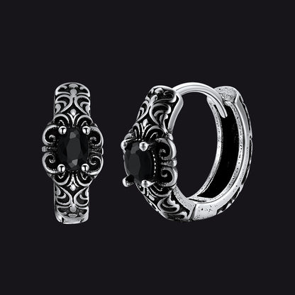 Pair of silver hoop earrings with black gemstones on a black background