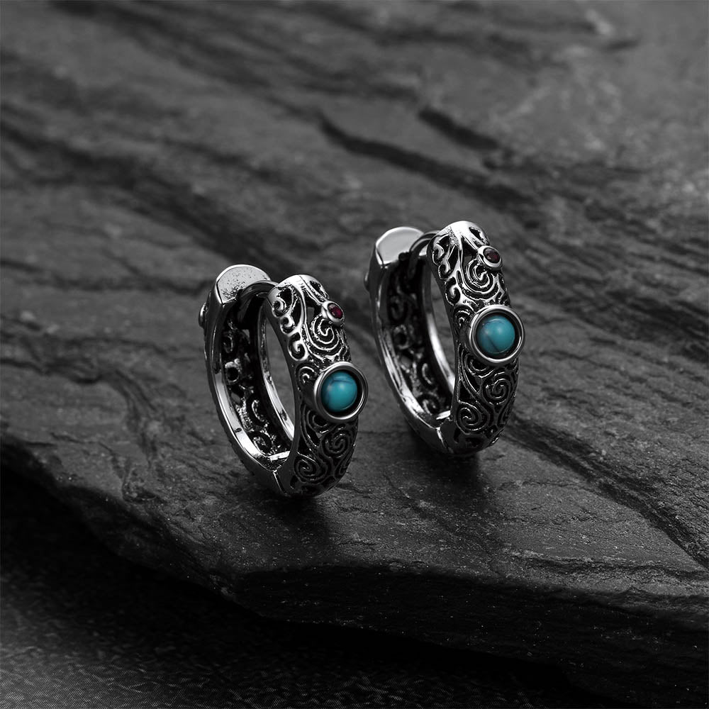 Silver hoop earrings with turquoise stones on a dark stone surface