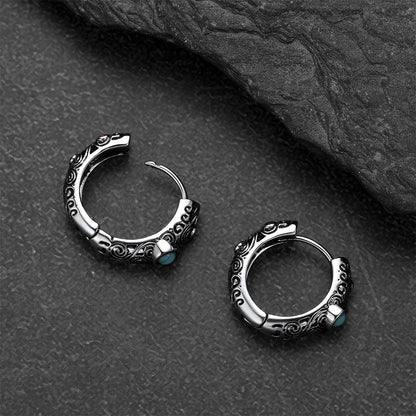 Silver hoop earrings with turquoise stones on a dark stone surface