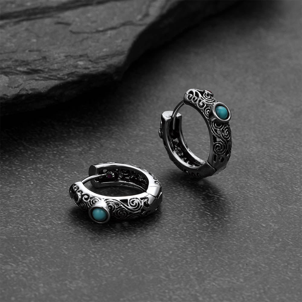 Silver hoop earrings with turquoise stones on a dark stone surface