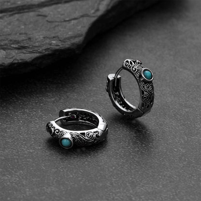 Silver hoop earrings with turquoise stones on a dark stone surface