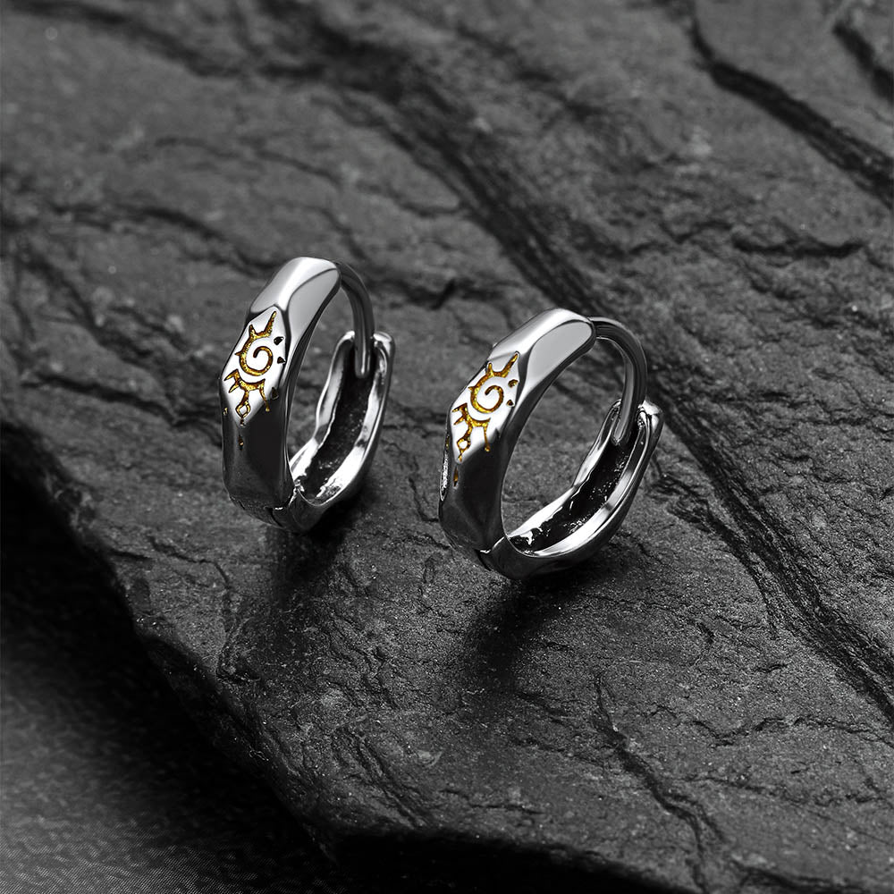 Pair of silver Wishing Stone Sun Pattern Hoop Earrings on a dark stone surface