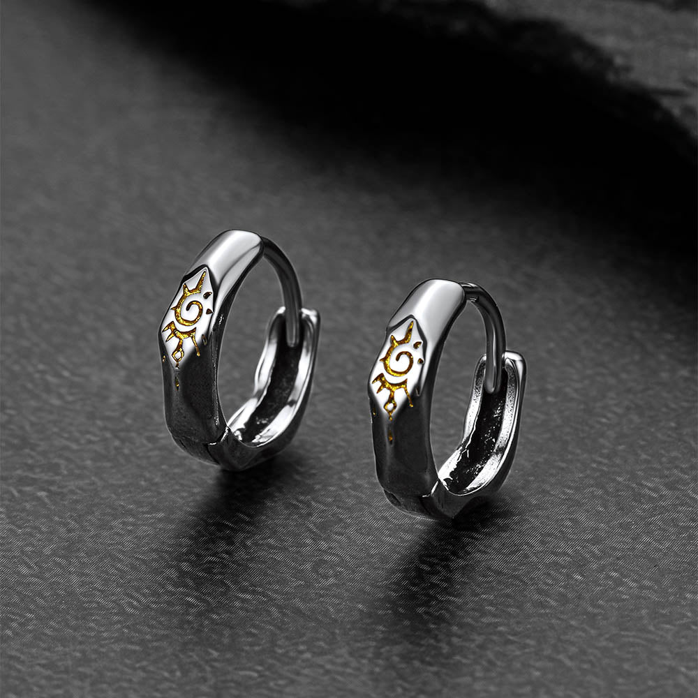 Pair of silver Wishing Stone Sun Pattern Hoop Earrings with gold accents on a dark surface