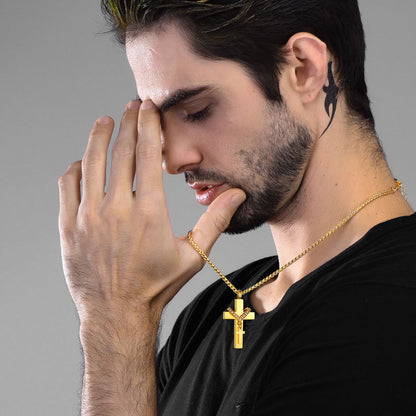 Man wearing a gold cross necklace with a cross pendant against a gray background