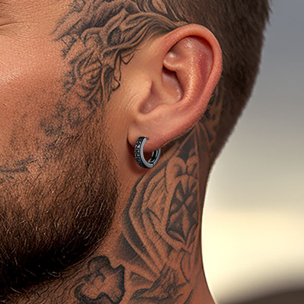 Close-up of a person's ear with a hoop earring and tattooed neck.